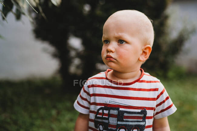 Portrait of beautiful boy with serious face looking to side outside — Stock Photo
