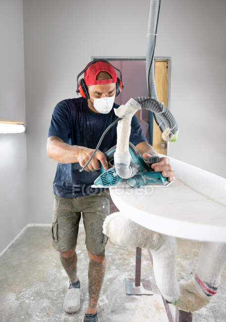 Surfboard Modeling Workshop - Man shaping a surfboard with a sander — Stock Photo