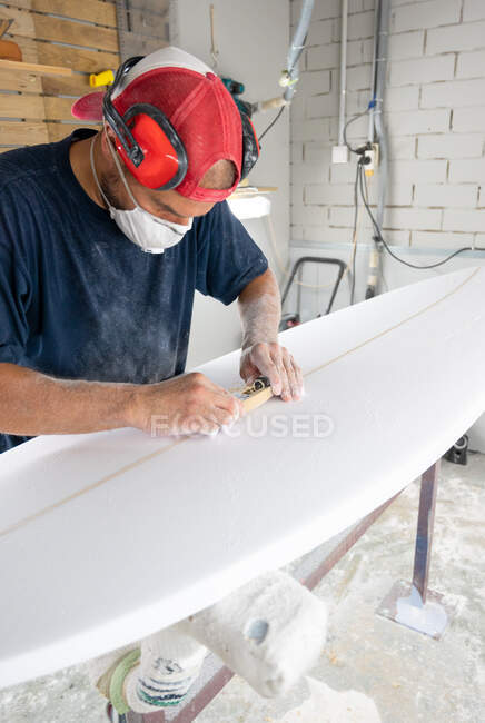 Workshop de modelagem de pranchas de surf - Homem aperfeiçoando a modelagem de uma prancha de surf — Fotografia de Stock