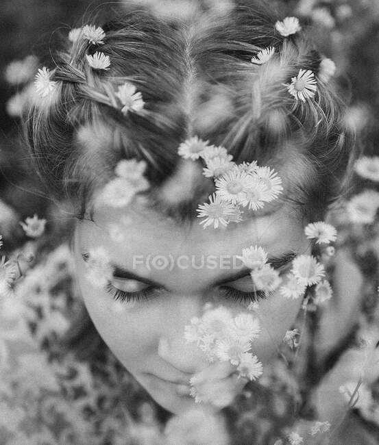 Young girl sitting in field of daisies — Stock Photo