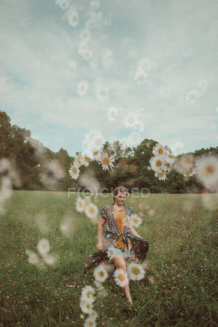 Chica retro paseando por un campo de flores silvestres - foto de stock