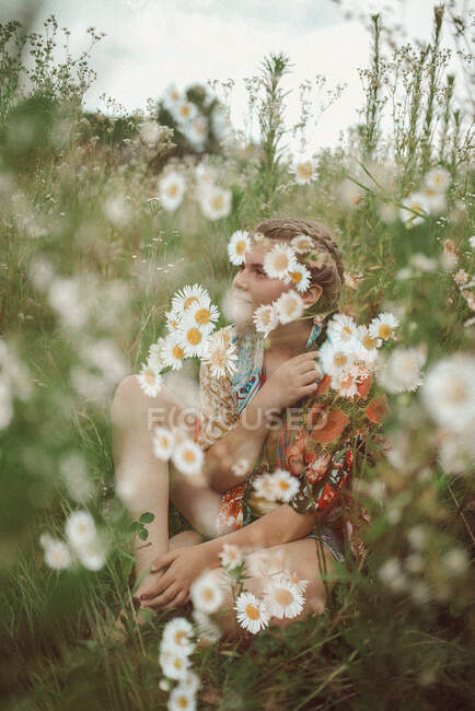 Fille rétro assis dans un champ de fleurs sauvages — Photo de stock