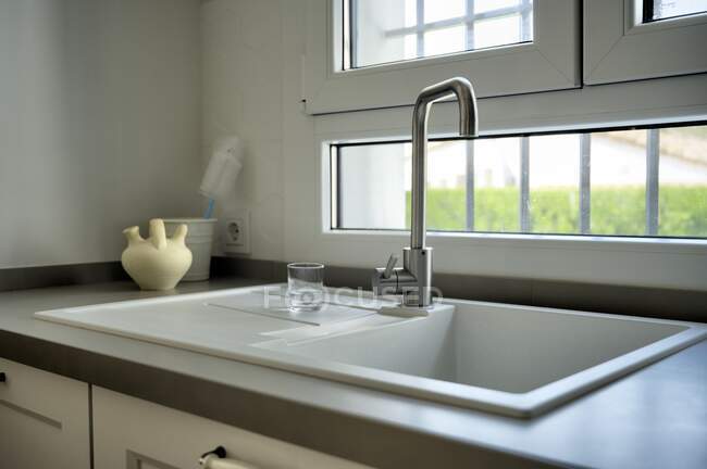 Cucina moderna con lavello bianco e una grande finestra — Foto stock
