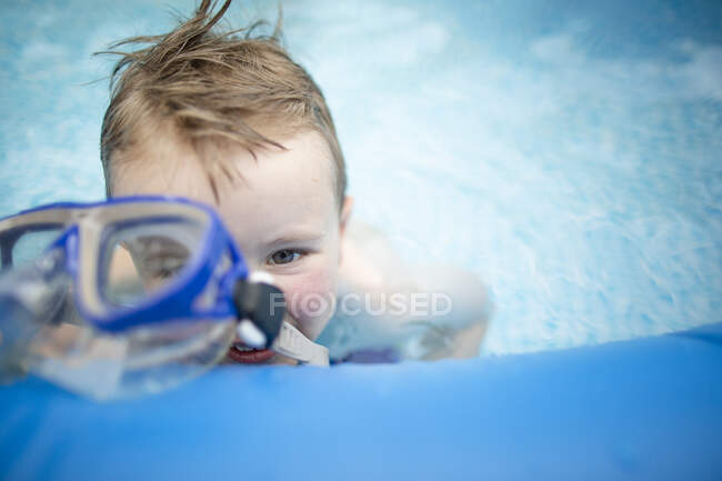 Niño durante el verano nadando en la piscina con gafas - foto de stock