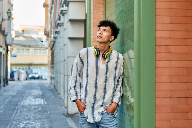 Jovem afro-haired homem com fones de ouvido olha para cima — Fotografia de Stock