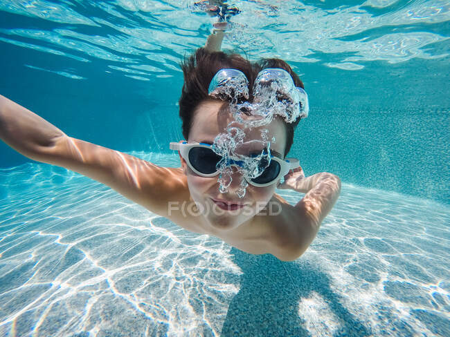 Immagine subacquea di un ragazzo che nuota in una piscina con gli occhiali. — Foto stock