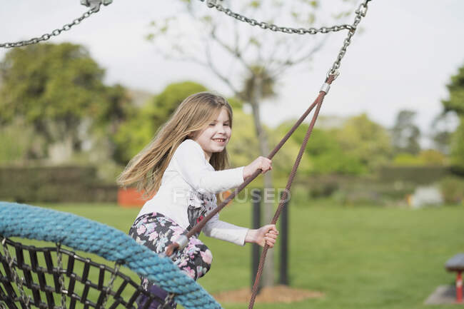 Chica joven jugando en un columpio en un parque infantil - foto de stock