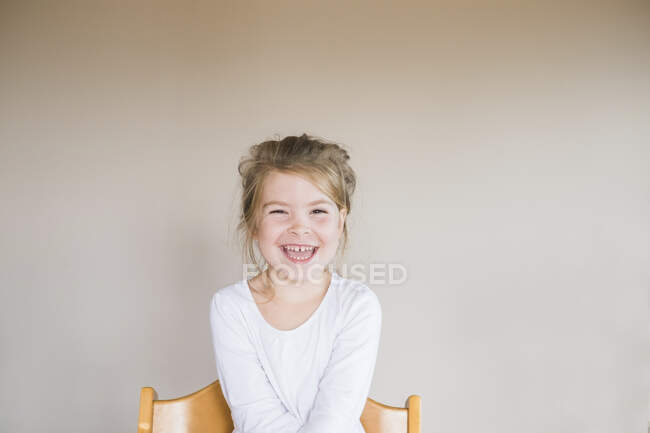 Портрет молодой девушки, сидящей и улыбающейся в камеру — стоковое фото