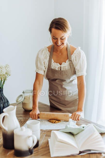 Retrato de la hermosa mujer haciendo masa para galletas en la cocina - foto de stock