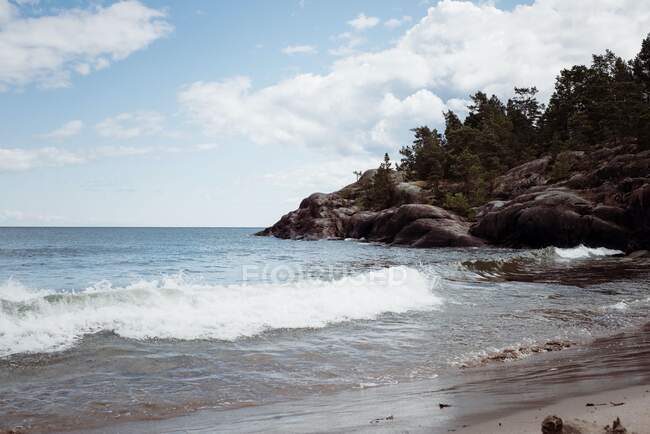 Rocky beach seaside in summer with cloudy sky — Stock Photo
