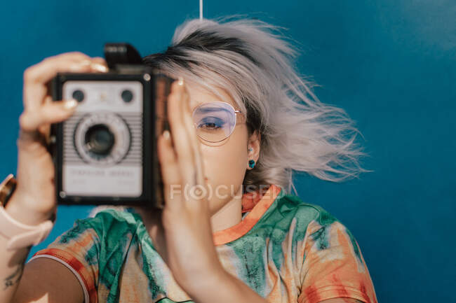 Uma jovem mulher tirando fotos com uma câmera analógica em um vestido colorido — Fotografia de Stock