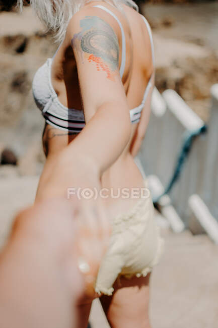 Um casal na praia anda de mãos dadas. Perspectiva do braço do homem — Fotografia de Stock