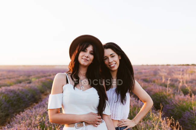 Подружки посміхаються і дивляться на камеру в лавандовому полі — стокове фото