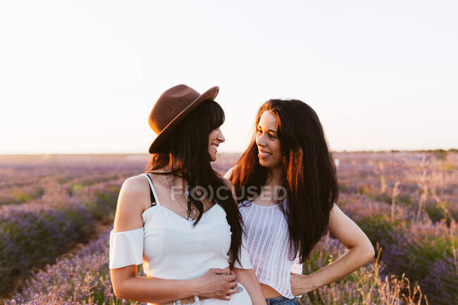 Подружки посміхаються і дивляться один одному в лавандовому полі — стокове фото
