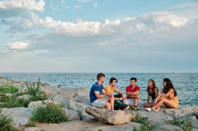 Groupe de jeunes au coucher du soleil sur la plage — Photo de stock