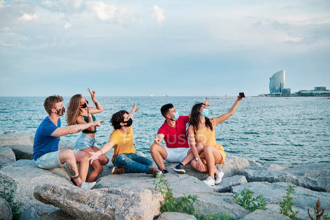 Eine Gruppe junger Leute mit Mundschutz für Coronavirus am Strand — Stockfoto