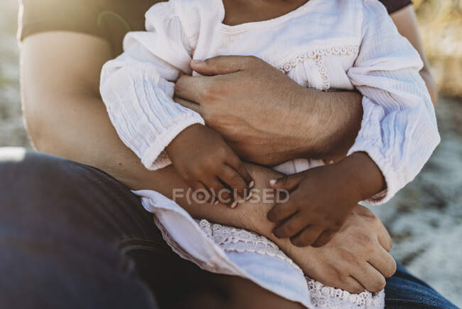 Close up detail of father embracing young child with arms wrapped — Stock Photo