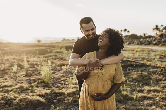 Jeune couple étreignant sur le coucher du soleil dans le champ — Photo de stock