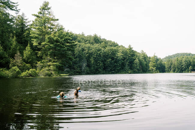 Un padre y sus hijos se refrescan en un pozo de natación oculto - foto de stock