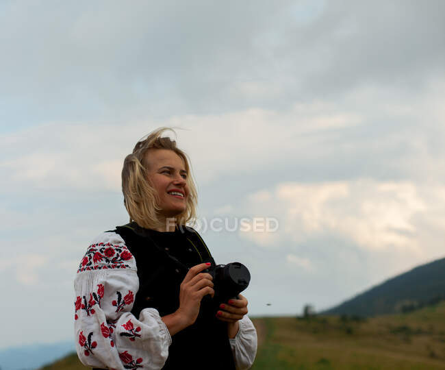 Girl photographer in the summer high in the mountains in the Ukrainian embroidery — Stock Photo