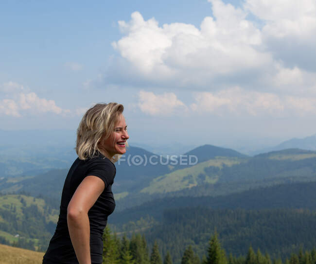 Веселый портрет девушки в обтягивающей футболке на фоне гор — стоковое фото