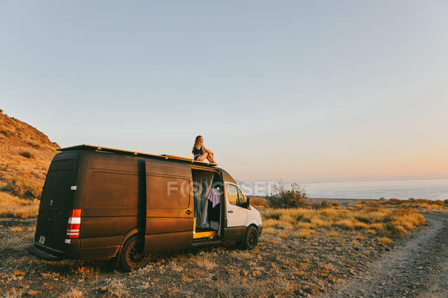 Jeune femme en camping-car regardant le lever du soleil à Baja, Mexique. — Photo de stock