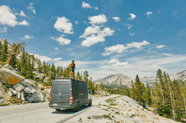 Jeune homme debout sur un camping-car regardant les vues sur le parc Yosemite. — Photo de stock