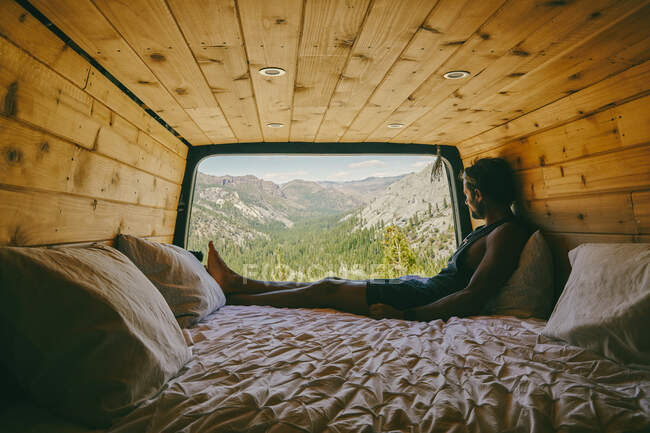 Junger Mann sitzt auf dem Bett eines Wohnmobils und beobachtet die Aussicht auf den Yosemite — Stockfoto