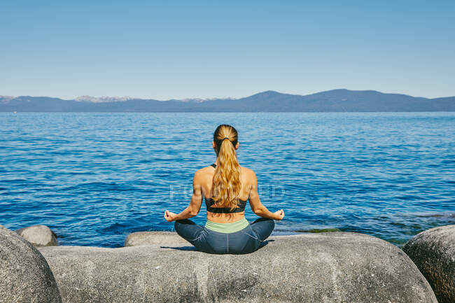 Jovem bela mulher praticando ioga junto ao lago — Fotografia de Stock
