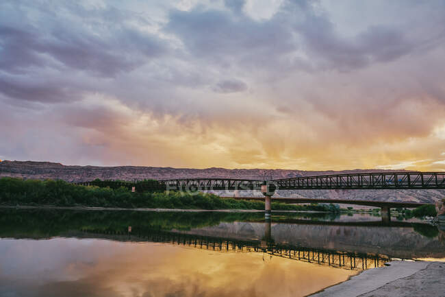 Brücke über den Fluss und Sonnenuntergang vor Naturkulisse — Stockfoto