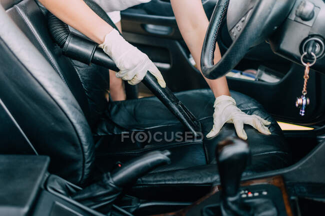 Молода жінка прибирає інтер'єр своєї машини за допомогою пилососа — стокове фото