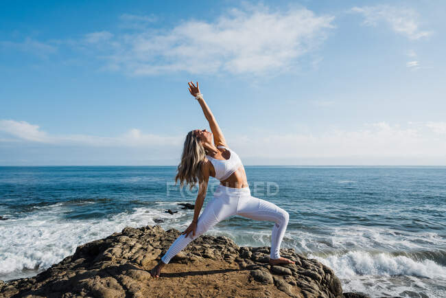 Красивая женщина практикующая йогу на пляже — стоковое фото