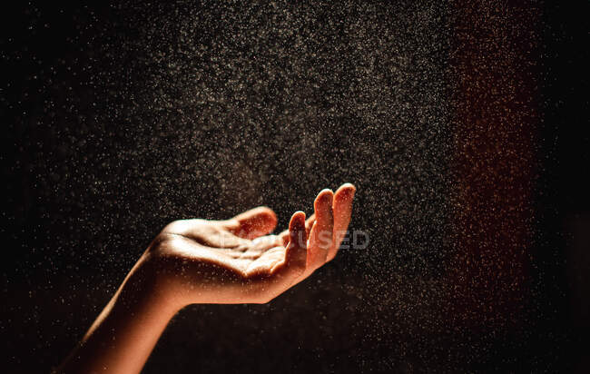 Hand with water drops on dark background — Stock Photo