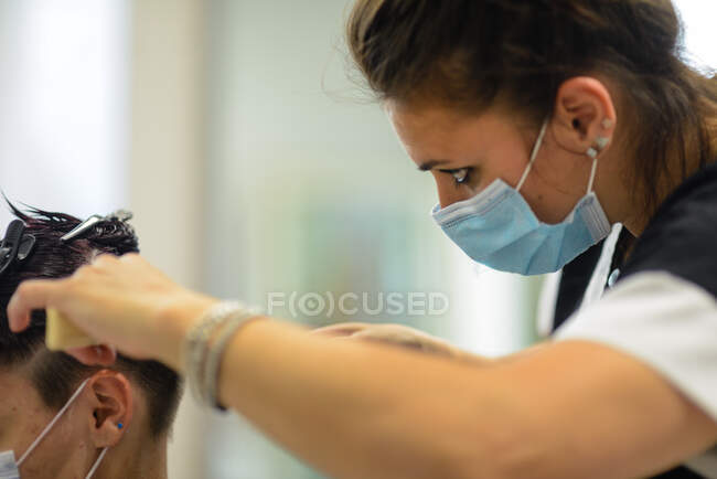 Female hair stylist at work cutting dying and styling young customer — Stock Photo
