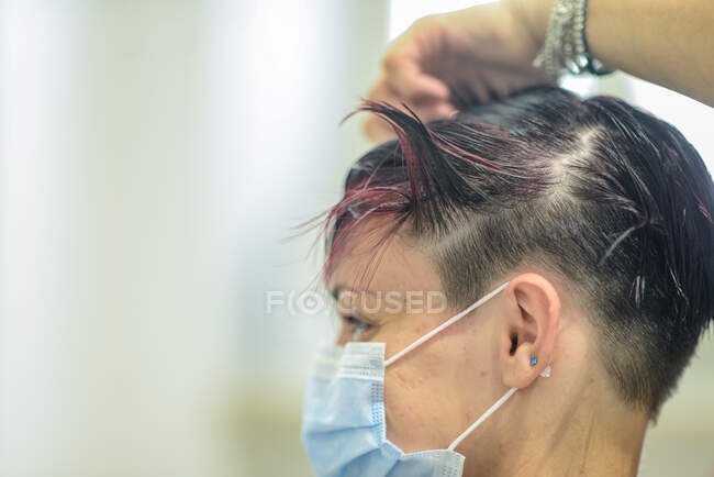 Young  female wearing face mask  in beauty salon cutting styling — Stock Photo