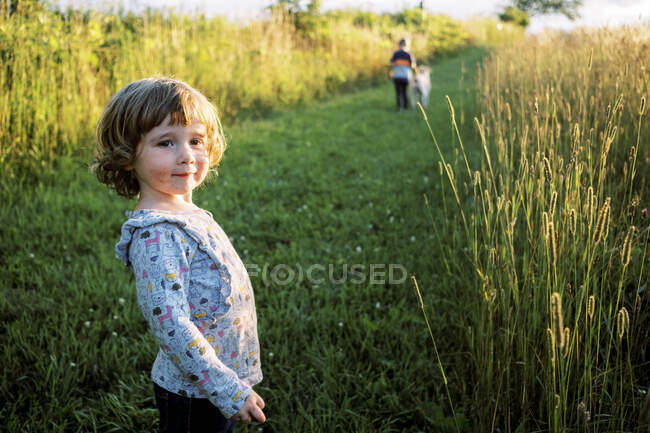 Ragazzina con una bocca spalmata e disordinata in piedi in un campo felicemente — Foto stock