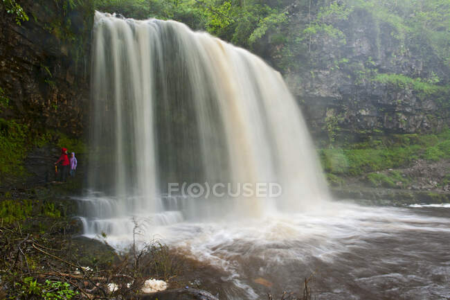Mother and daughter walking behind Sgwd yr Eira waterfall — Stock Photo