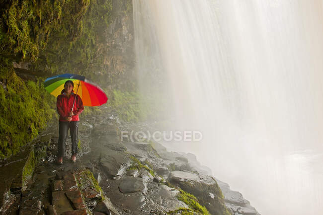 Mujer detrás de la cascada Sgwd yr Eira en los Brecon Beacons en Gales - foto de stock