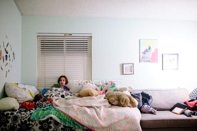 Teenie-Mädchen liegt mit ihrer Katze im Bett, während sie Videospiele spielt — Stockfoto