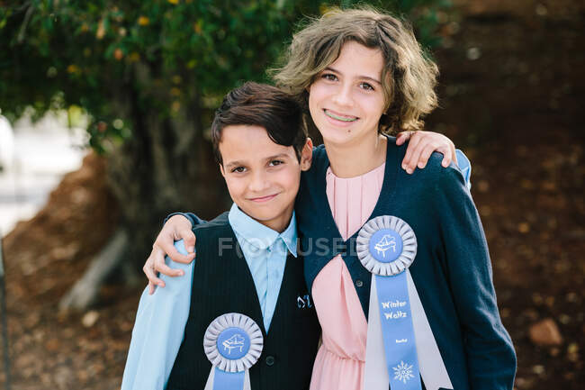 Brother and sister smile for the camera with their recital ribbons — Stock Photo