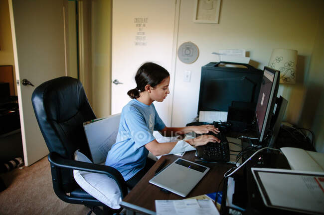 Tween menina senta-se em um computador desktop digitação — Fotografia de Stock