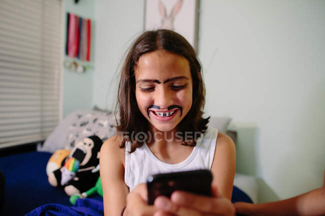 Девочка-подросток смеется, делая селфи на телефоне с дурацким гримом — стоковое фото