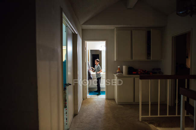 Rapaz olha para fora da casa de banho depois de secar as mãos à noite — Fotografia de Stock