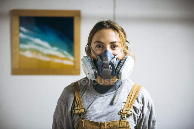 Retrato de artista de resina femenina en estudio de arte casero con respirador - foto de stock