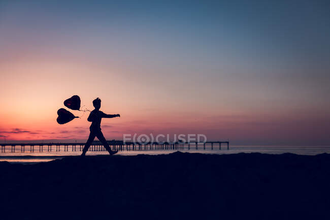 Mignon garçon avec ballons au coucher du soleil — Photo de stock