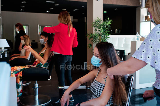 Gruppe weiblicher Kunden mit sozialer Distanz und Gesichtsmaske im Friseursalon — Stockfoto