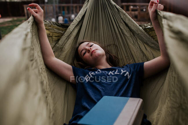 Дівчина-підліток лежить в гамаку з книгою — стокове фото