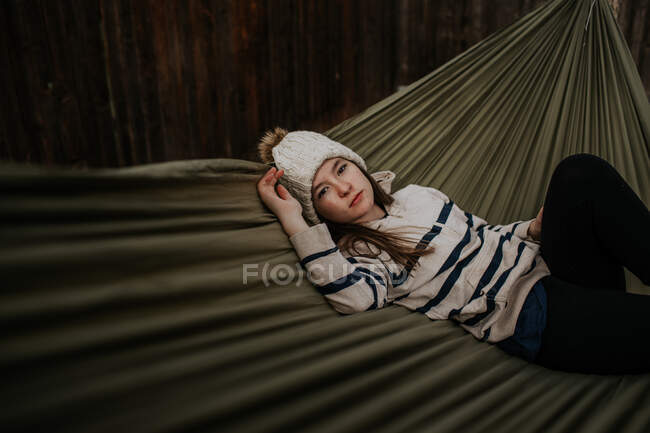 Teen girl laying in hammock with sweater and hat — Stock Photo