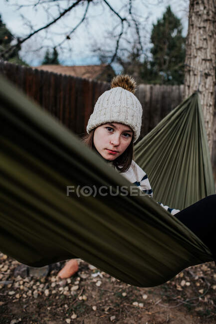 Vertical portrait of preteen girl looking over hammock — Stock Photo