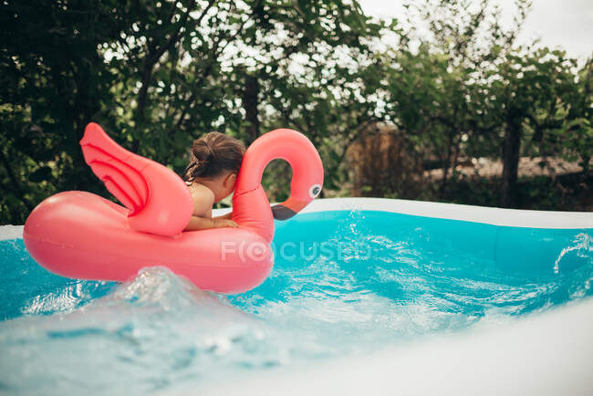 Pouco brincando na piscina com flamingo brinquedo de água. — Fotografia de Stock